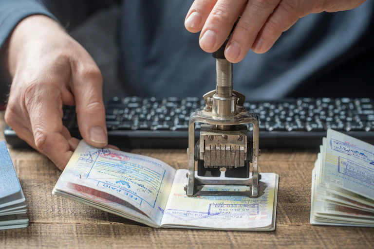 Close up photo of the hands of a border control officer putting a stamp in a passport