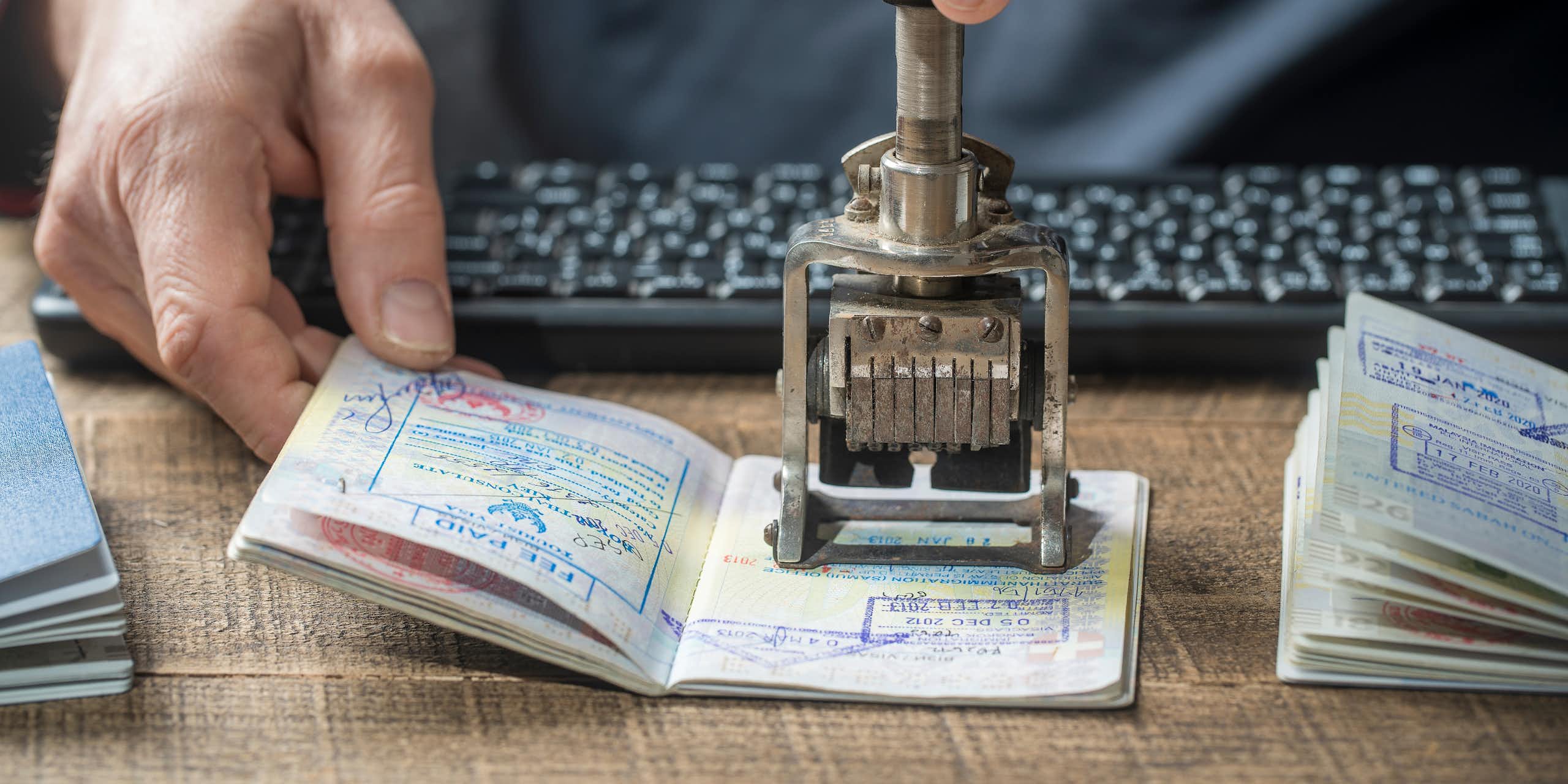 Close up photo of the hands of a border control officer putting a stamp in a passport