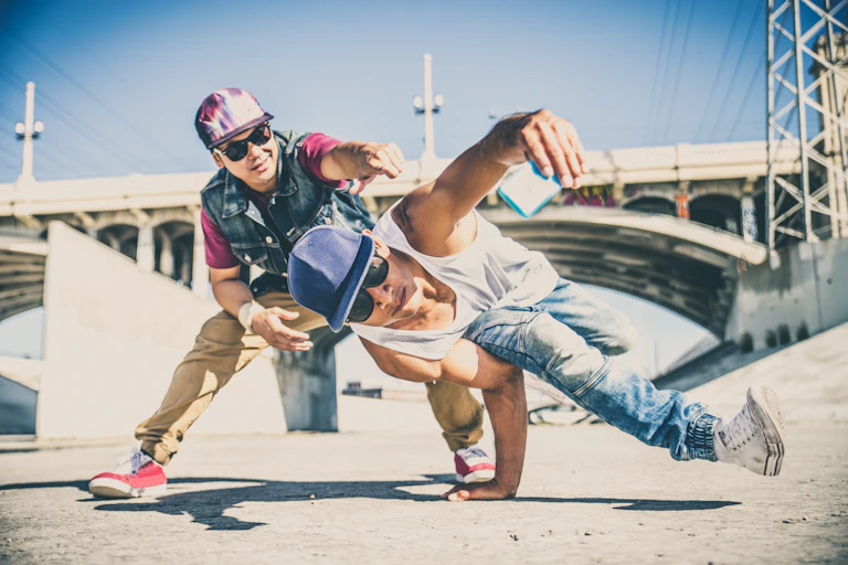 Two men breakdancing in a storm drain.