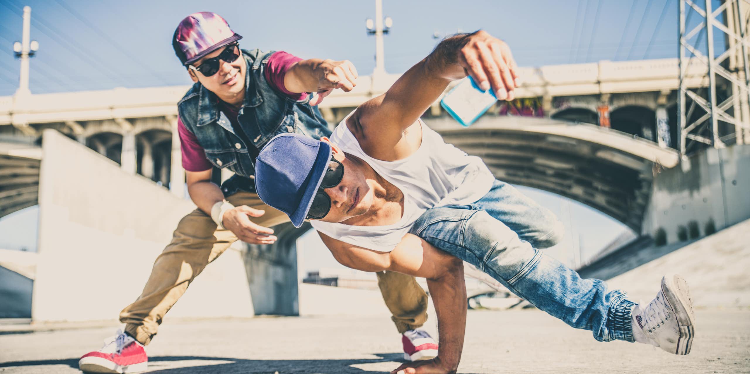 Two men breakdancing in a storm drain.