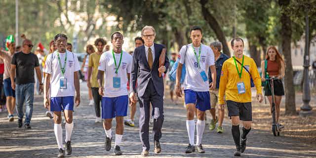 A still from The Beautiful Game of England team members in the Homelessness World Cup walk with their manager.