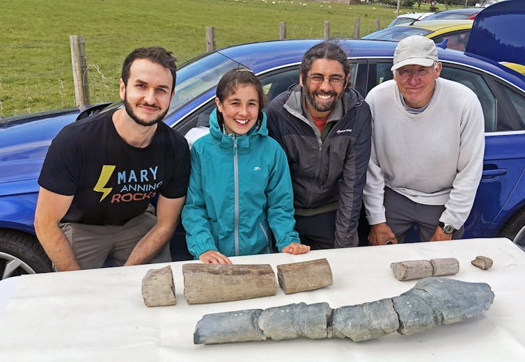 Four people sat at a table with large fossil bones