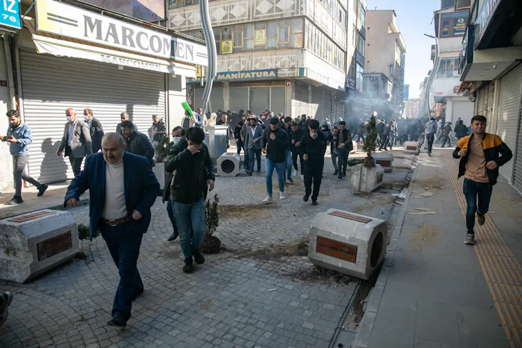 People run down a street after clashes with security forces.