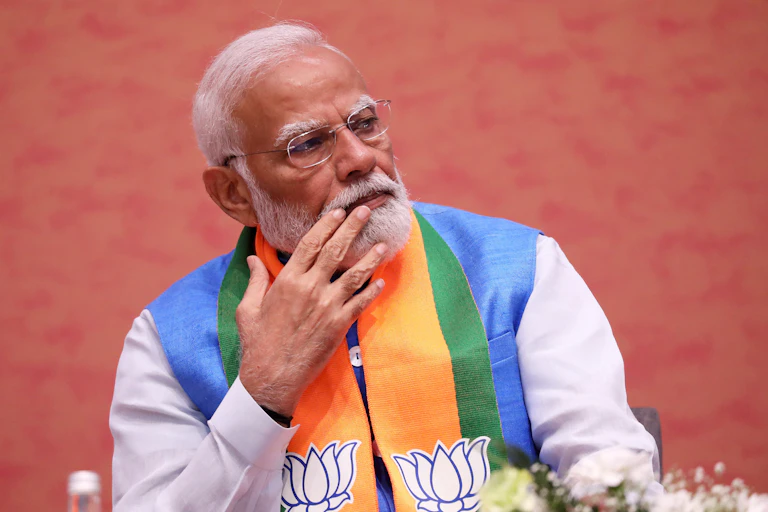 Narendra Modi sat in colourful attire stroking his beard.