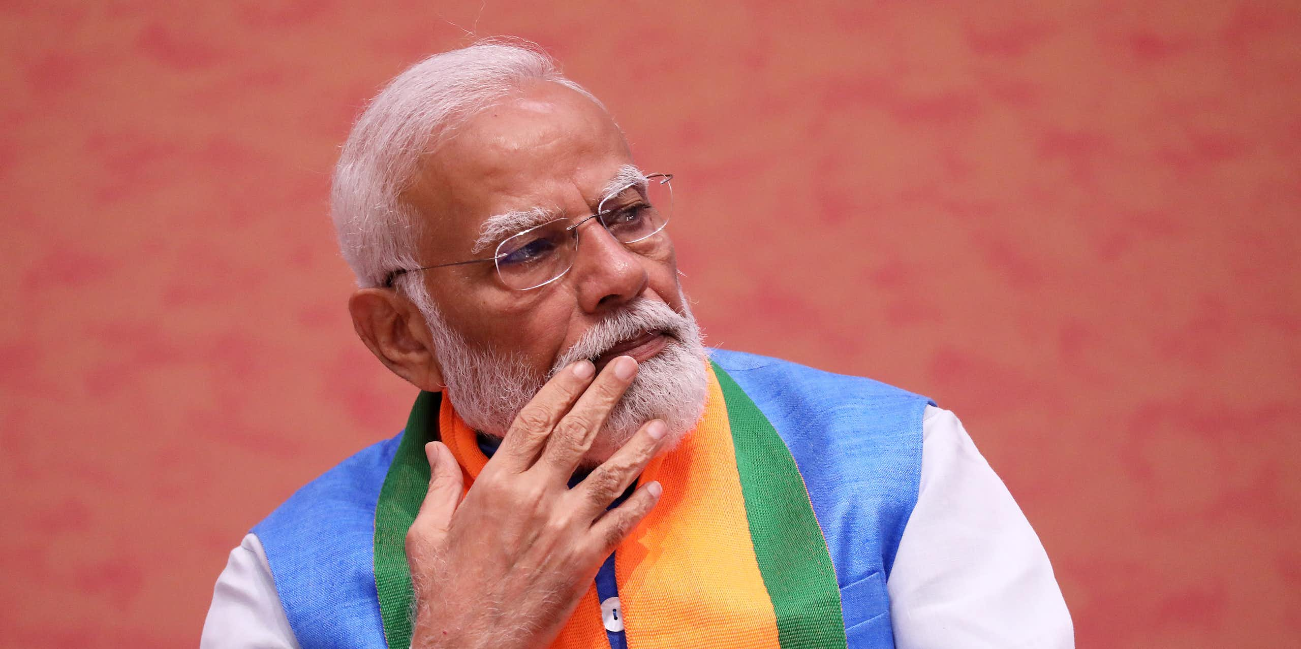 Narendra Modi sat in colourful attire stroking his beard.