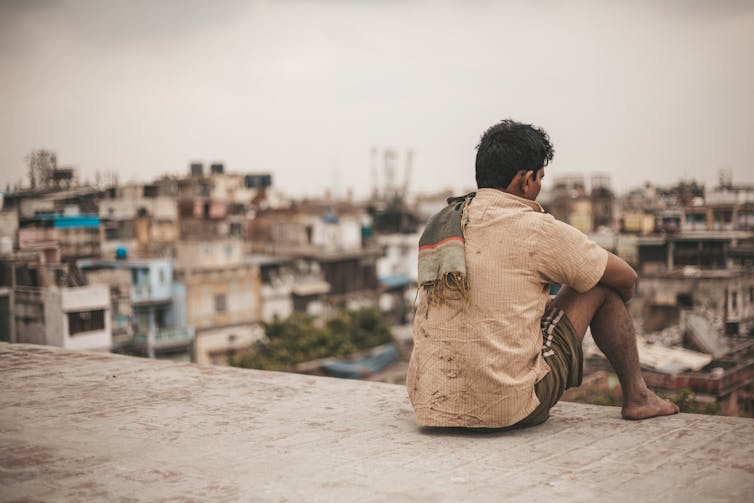 An Indian man sitting on a rooftop.