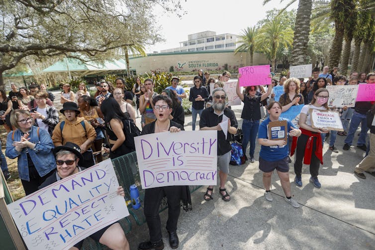 People at a protest carry placards reading: diversity is democracy