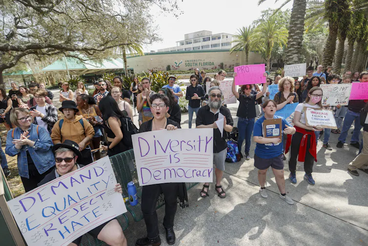 People at a protest carry placards reading: diversity is democracy