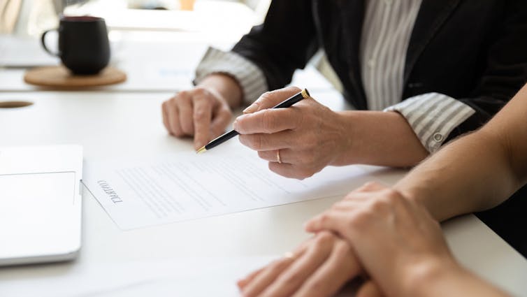 Two people look at the document, one has to sign it