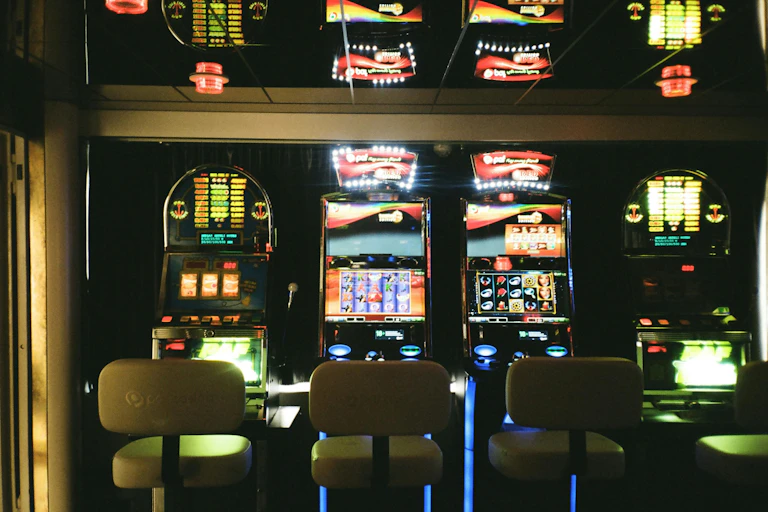 Three empty chairs in front of pokies machines.