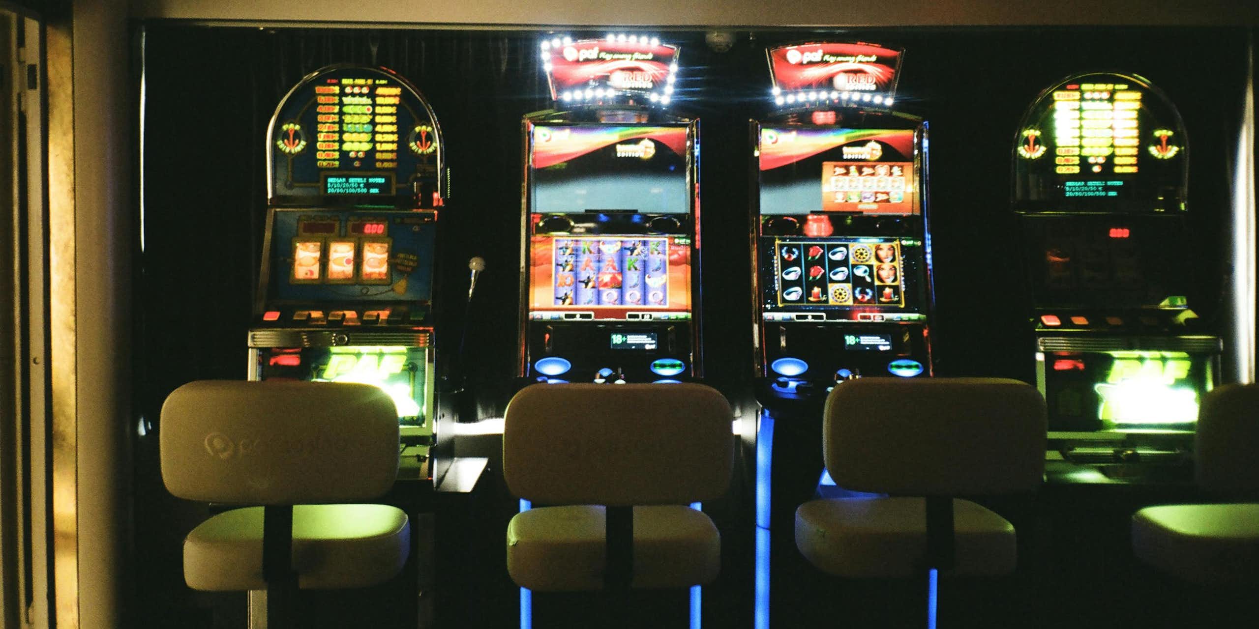 Three empty chairs in front of pokies machines.
