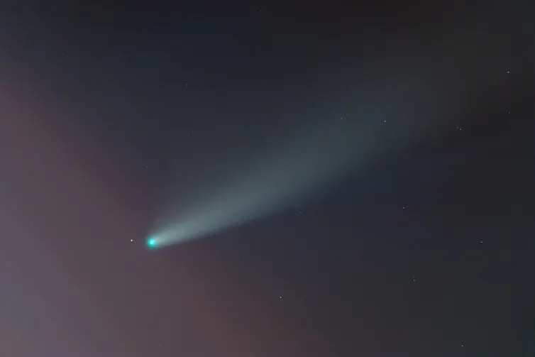 A green dot with a long white smudge behind it on a black background.