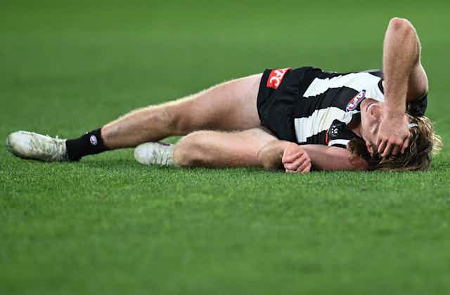 Collingwood player Nathan Murphy lays injured during a game
