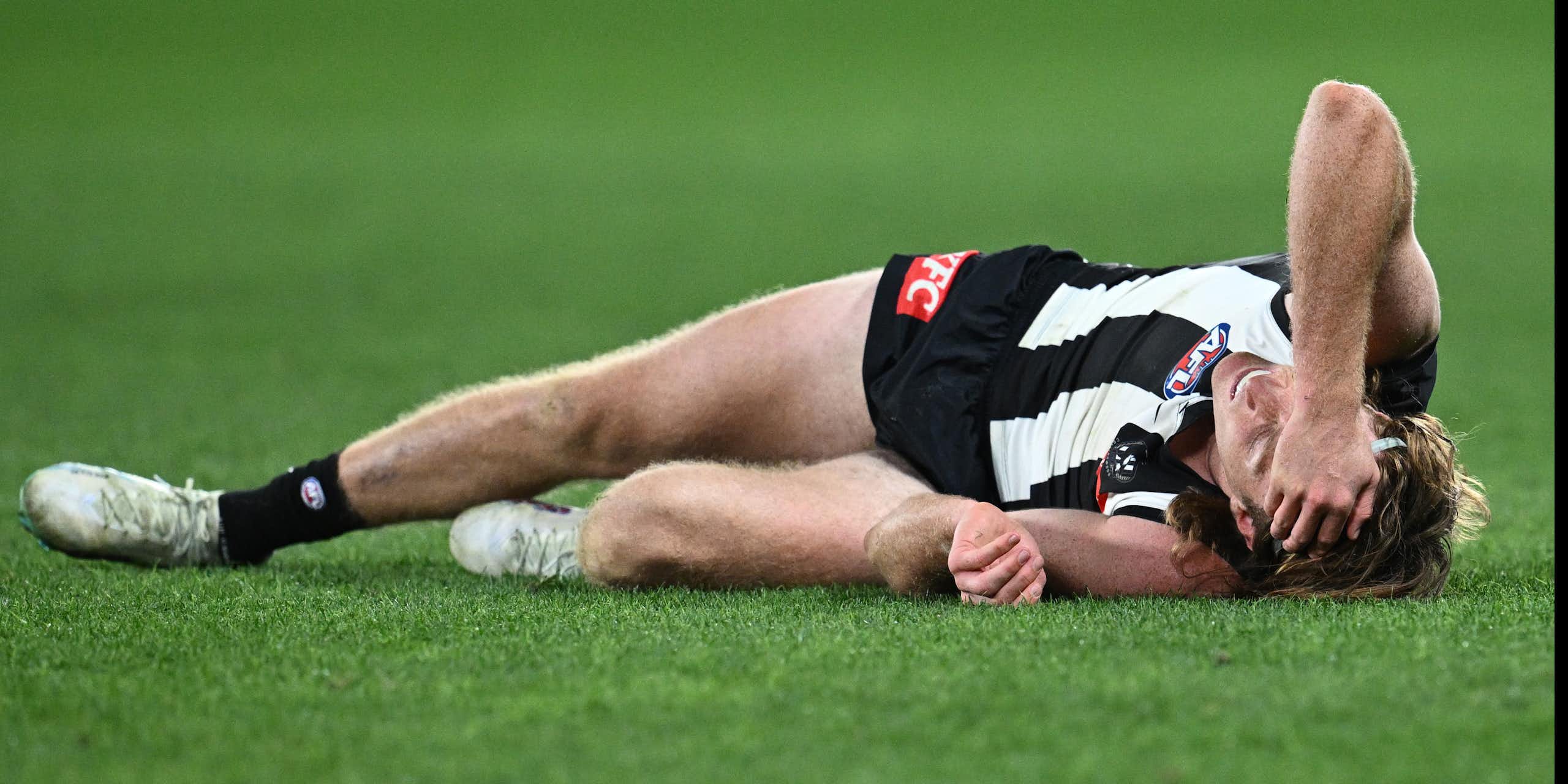 Collingwood player Nathan Murphy lays injured during a game