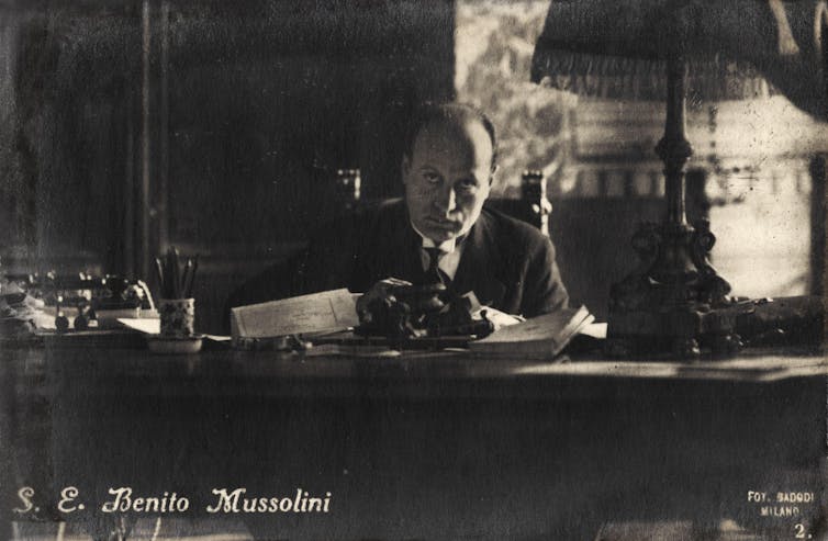 El líder italiano Benito Mussolini sentado ante su escritorio
