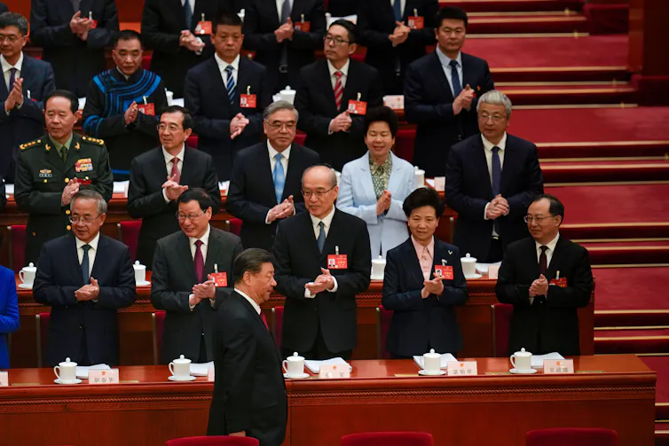 China's president Xi during the opening session of the National People's Congress at the Great Hall of the People in Beijing, China, in March 2024, walking past a group of people who are clapping.
