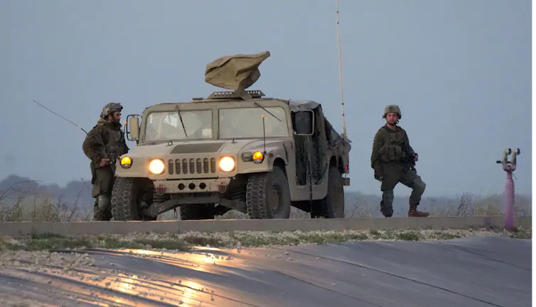 Two Israeli soldiers and an armoured car on patrol in the Gaza Strip.