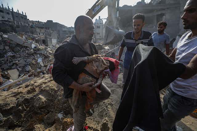 A Palestinian man carries the body of a baby recovered from the rubble of the Jabalia refugee camp, one day after an airstrike hit the area, in northern Gaza, 01 November 2023.