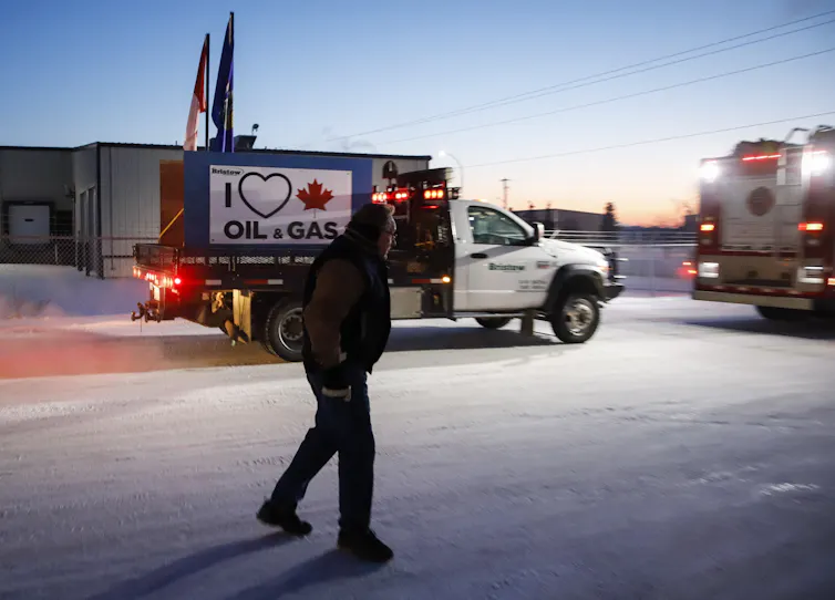 A man walks past a truck in the snow.