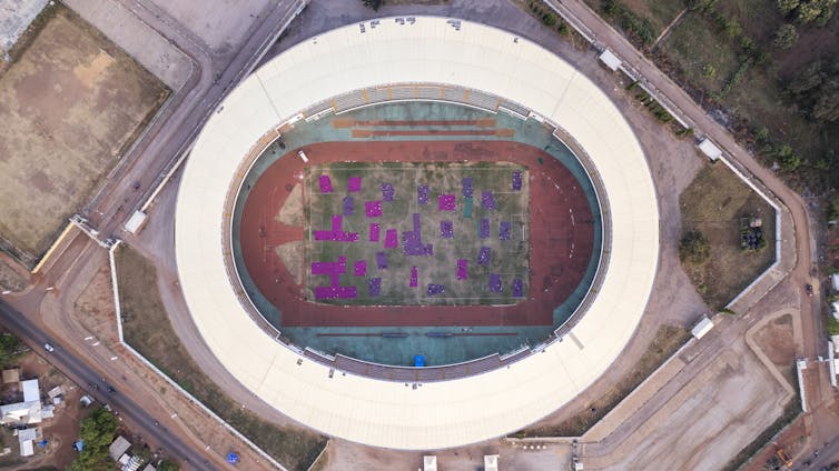 Sheets of purple fabric in a football stadium, viewed from the sky.
