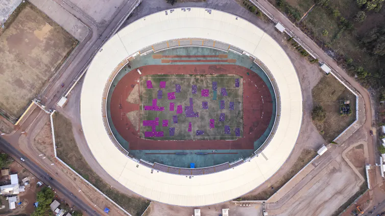 Sheets of purple fabric in a football stadium, viewed from the sky.