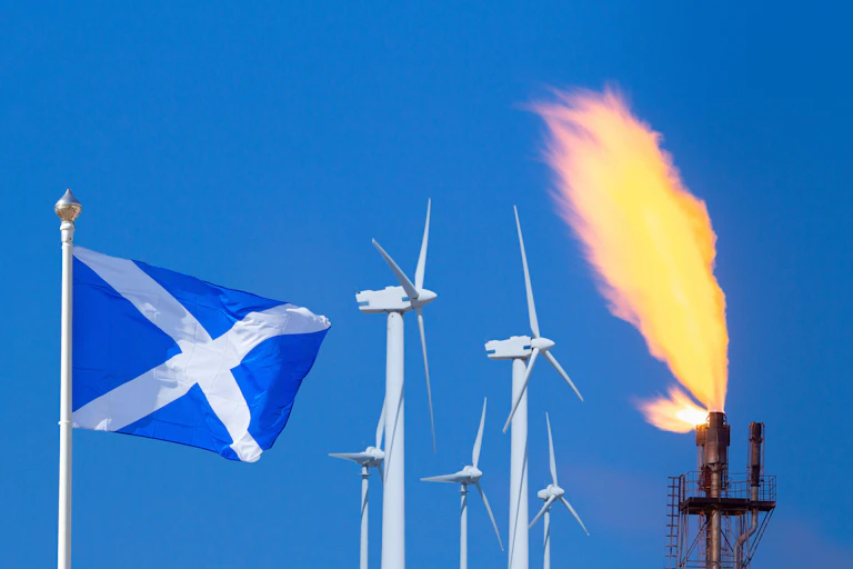 A Scottish flag next to wind turbines and a gas flare.