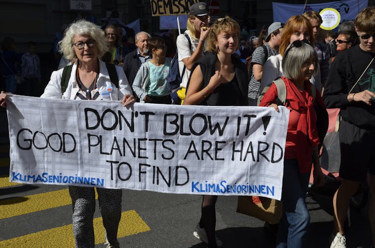 Women holding a banner reading 'don't blow it! Good planets are hard to find'.