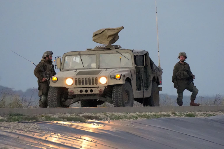 Two Israeli soldiers and an armoured car on patrol in the Gaza Strip.