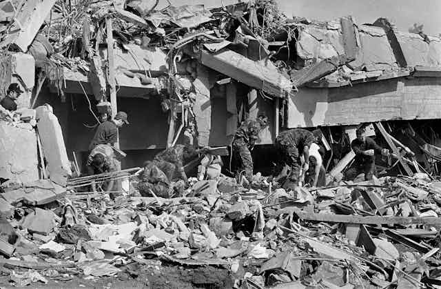 Men in fatigues sort through rubble
