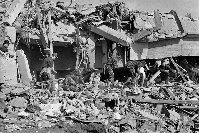 Men in fatigues sort through rubble
