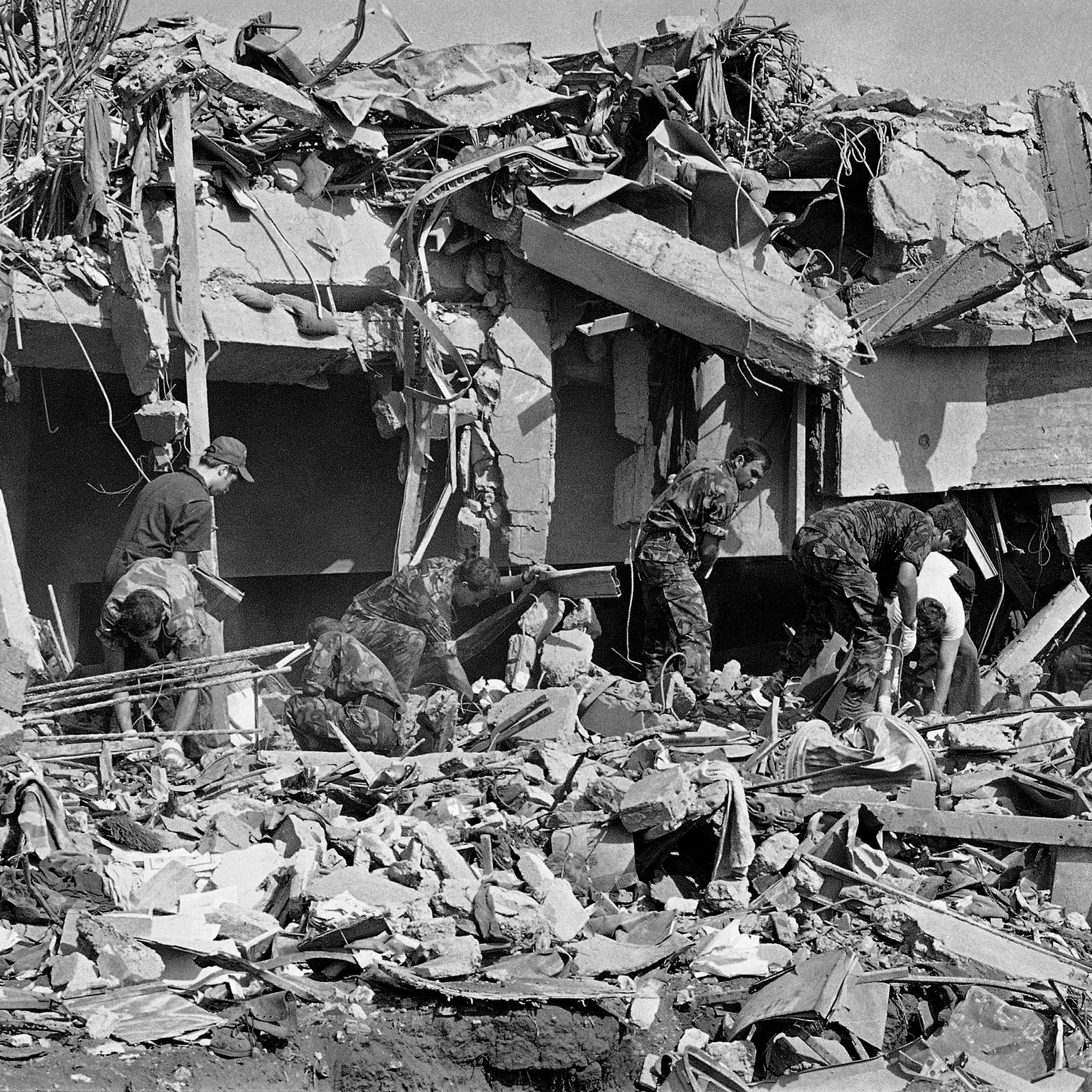 Men in fatigues sort through rubble
