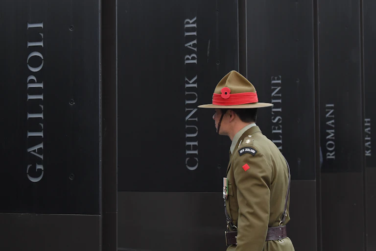 New Zealand soldier in front of World War 1 memorial showing battle names