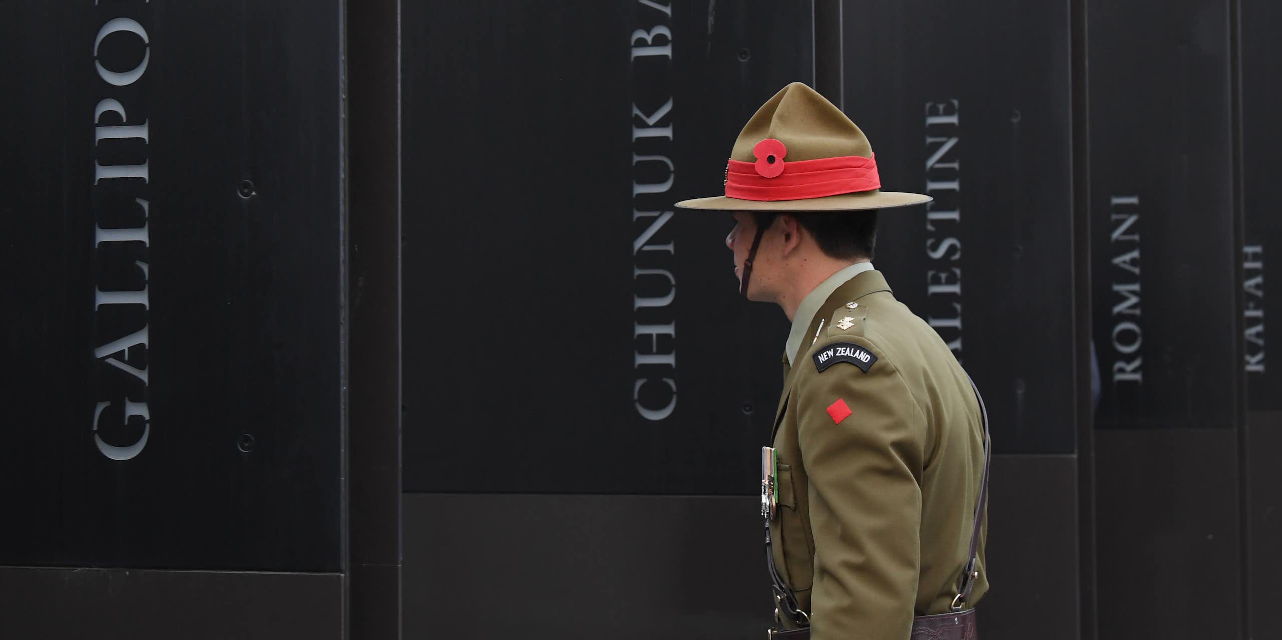 New Zealand soldier in front of World War 1 memorial showing battle names