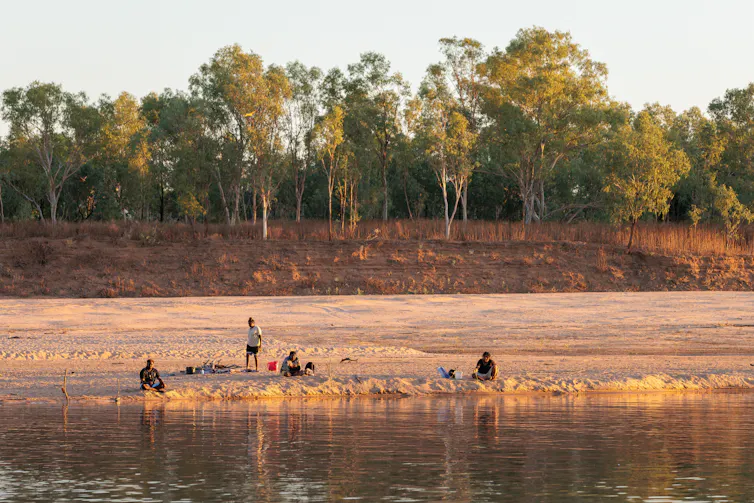 A couple of people in the Australian outback on the banks of a river.
