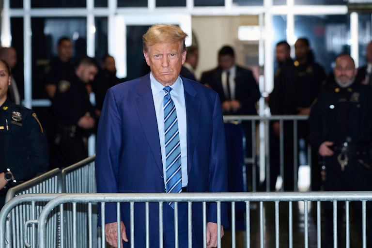 Donald Trump in a blue suit near to a court.