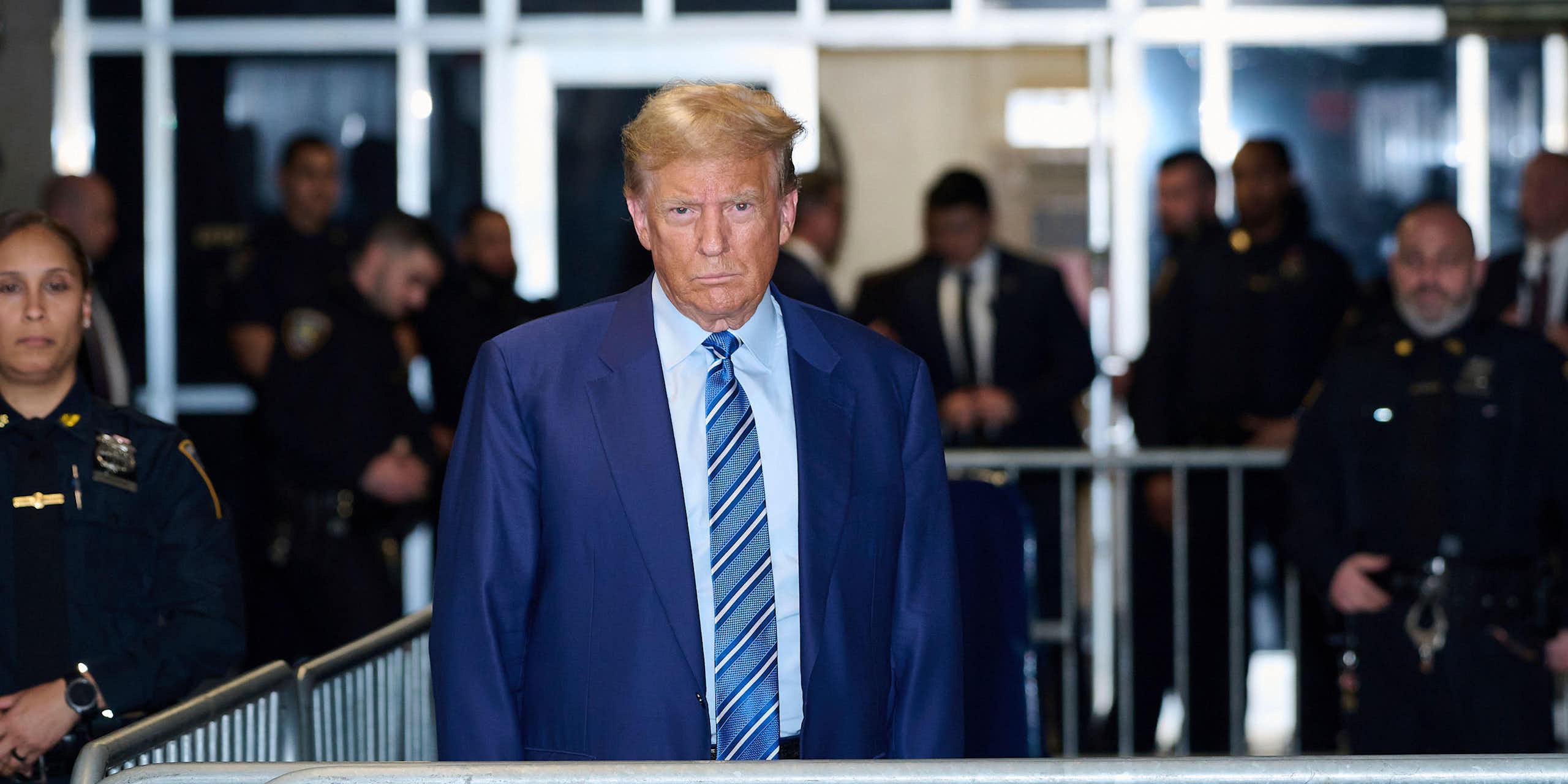 Donald Trump in a blue suit near to a court.