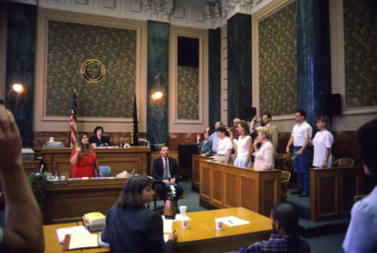 Jurors stand up and raise the hands to be sworn in for a case in Oregon.