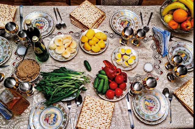 A table set with plates of fruit, vegetables, eggs and flatbread.