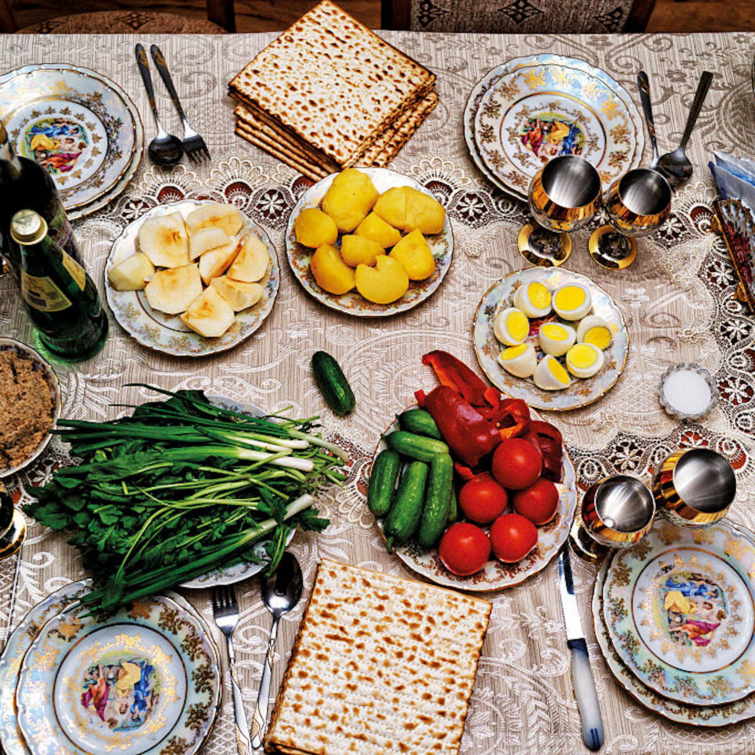 A table set with plates of fruit, vegetables, eggs and flatbread.
