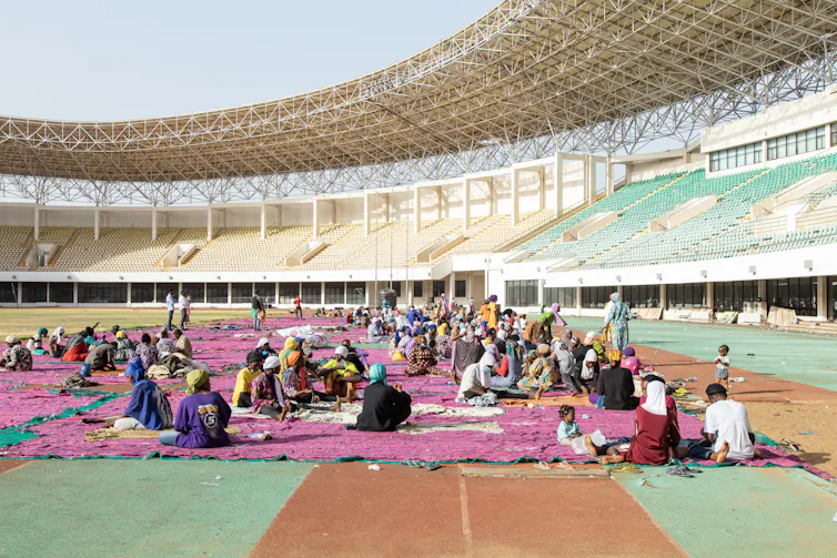 People working on purple fabric in a football stadium