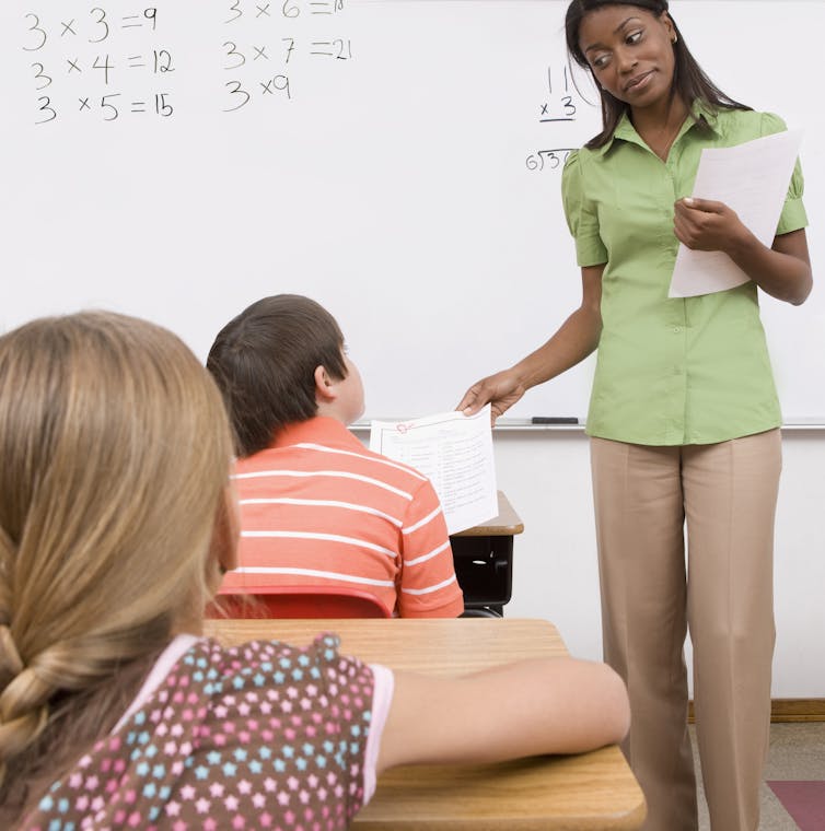 A teacher hands a student a paper with a low grade.