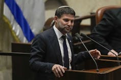 A man wearing a yarmulke speaks into a microphone.