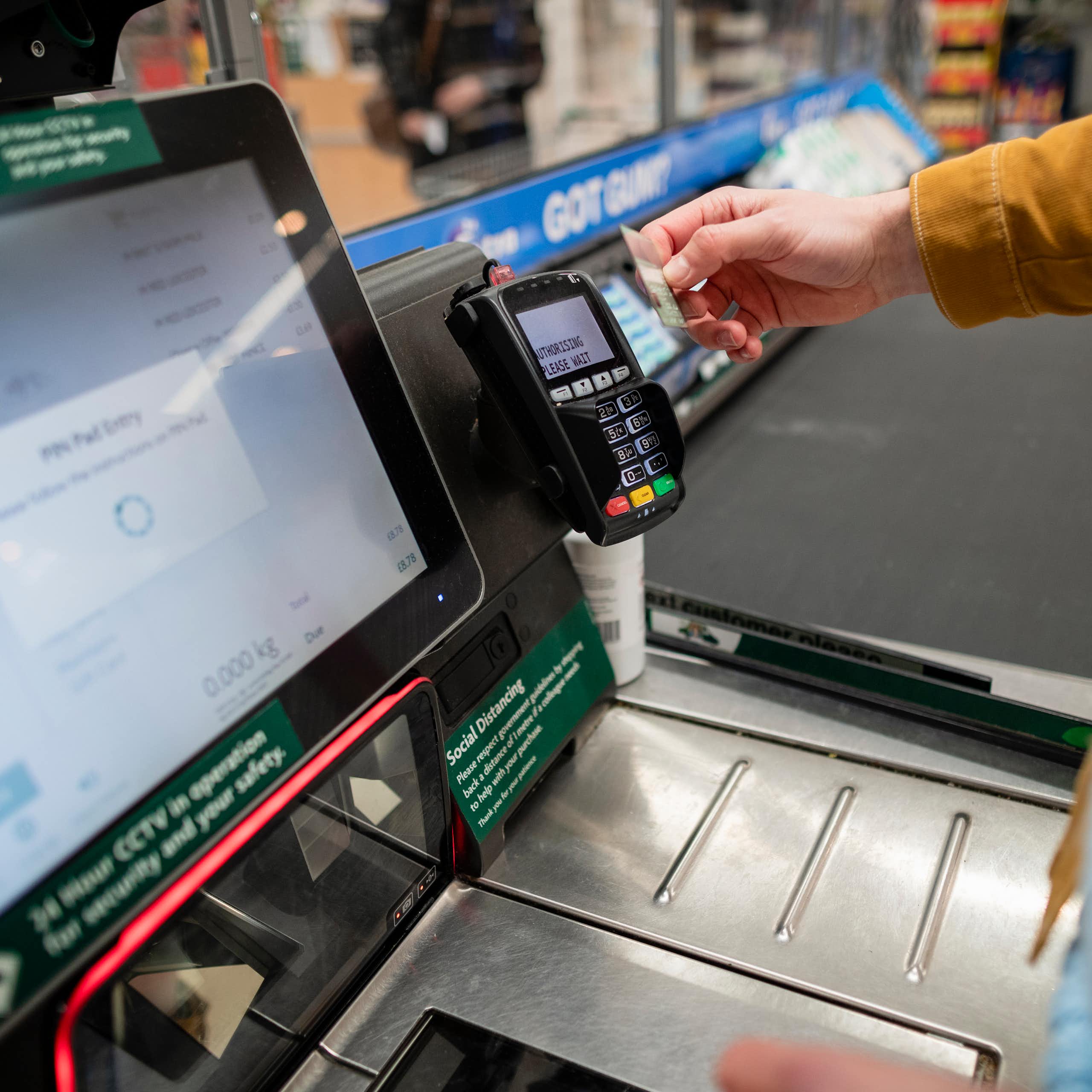 Person paying at supermarket self-checkout