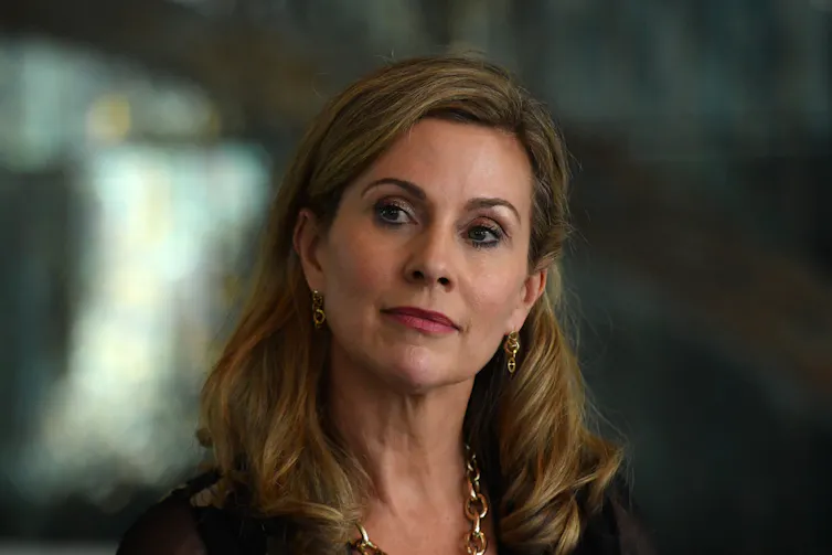 A woman with shoulder-length light brown hair looks on