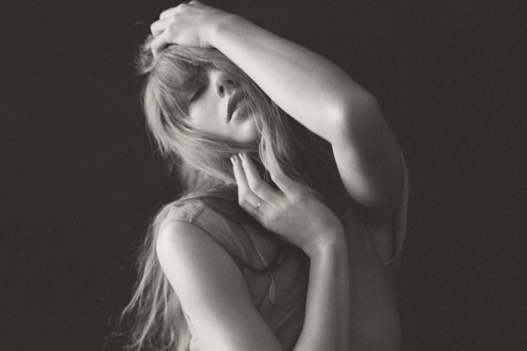 Taylor Swift raising her arms in a tortured artist pose