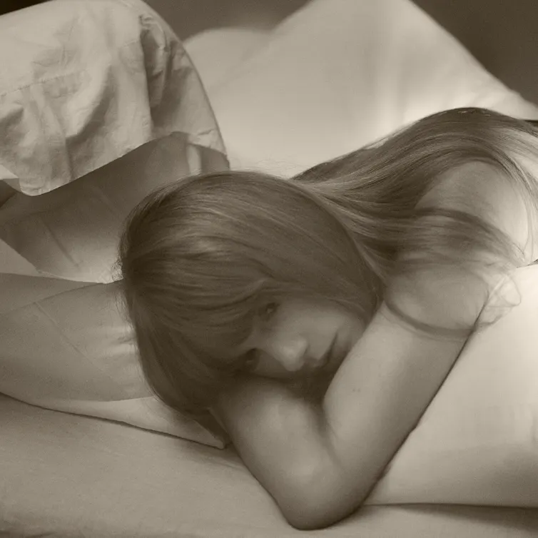 Taylor lying in a bed looking mournful.