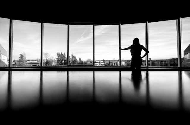 A person silhouetted against a window in an office environment