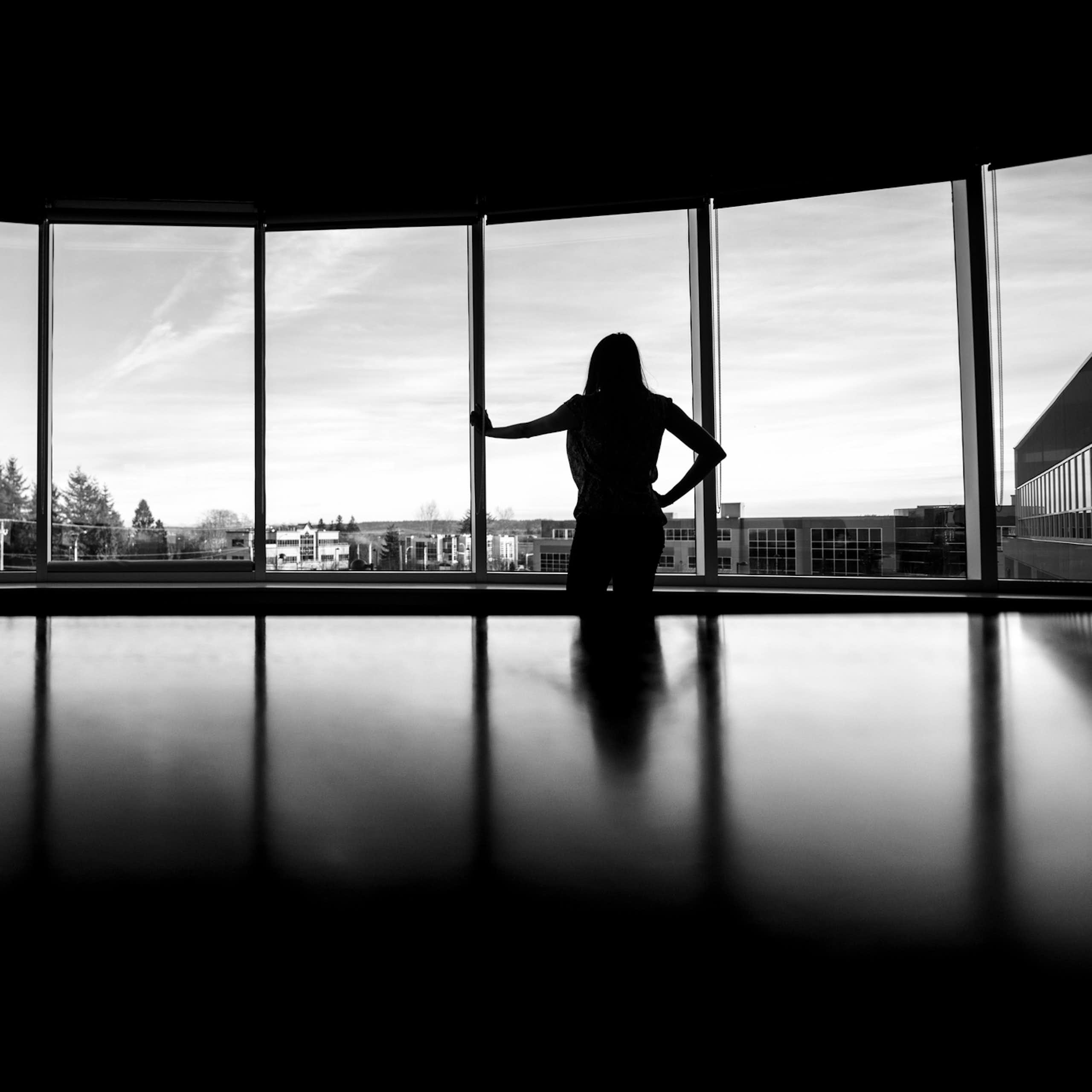 A person silhouetted against a window in an office environment