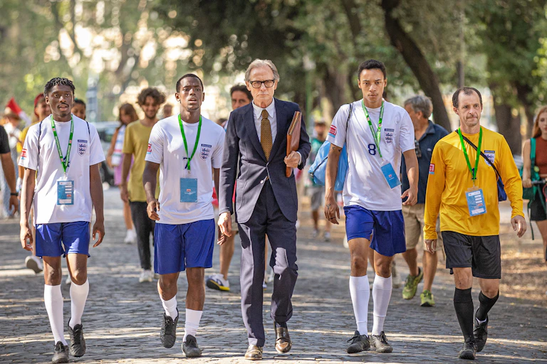 A still from The Beautiful Game of England team members in the Homelessness World Cup walk with their manager.