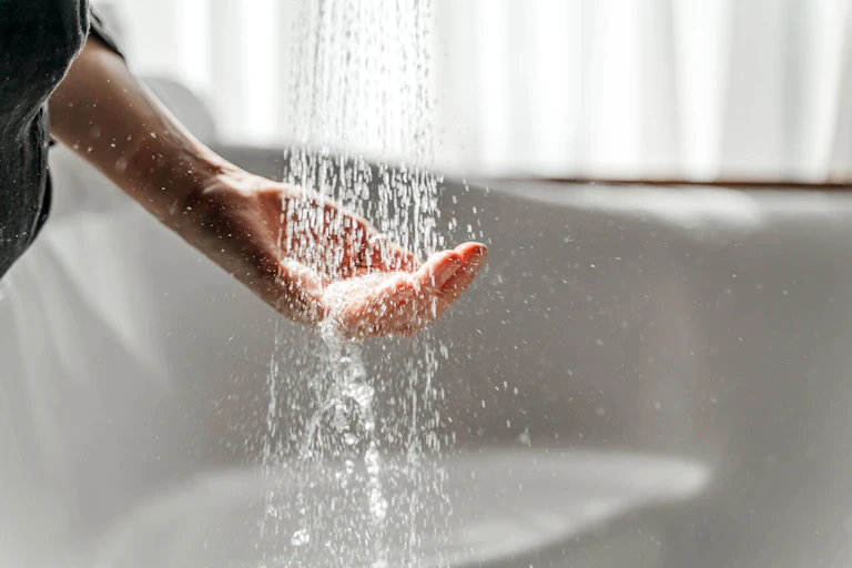 A hand under a shower of water.